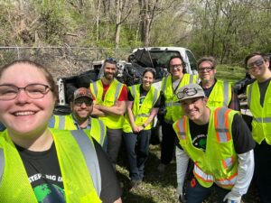 Volunteers posing after a cleanup event, with bags of collected litter in the truck behind them.