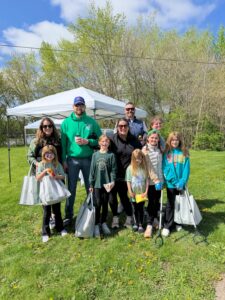 Volunteers of different ages posing with their trash collection bags during a community cleanup event.