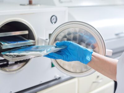 Female nurse doing sterilization of dental medical instruments in autoclave. Sterilization department at dental clinic