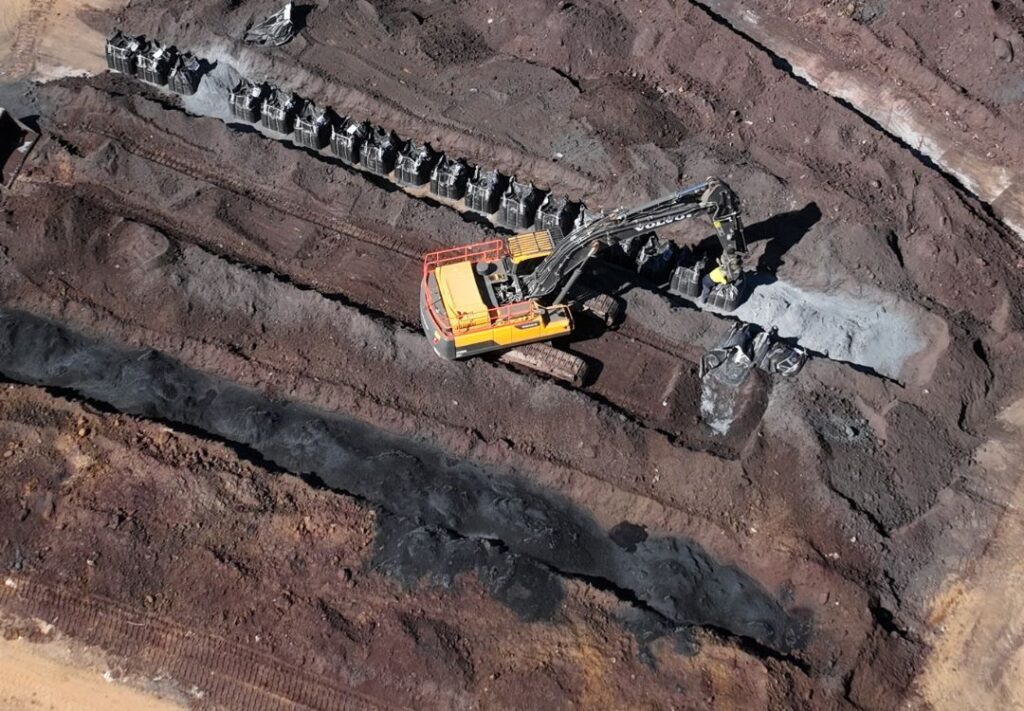 An excavator mixing amendment through contaminated soil.