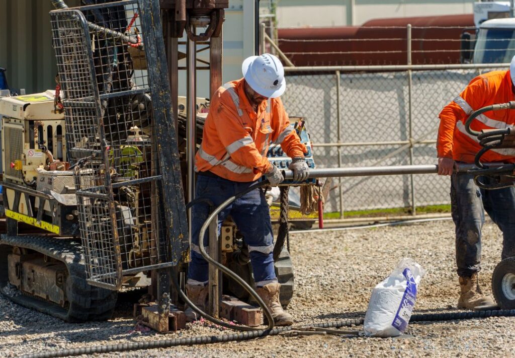Site operators running injection rods from a direct-push rig during a groundwater treatment program.