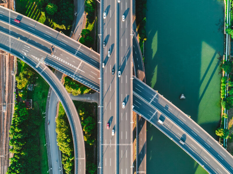 Aerial view of a multi-level highway interchange beside a river surrounded by greenery.