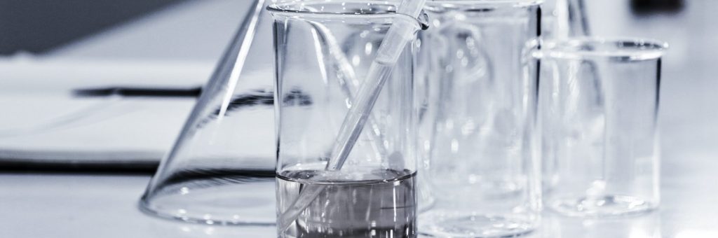 various sized beakers filled with liquid and pipet